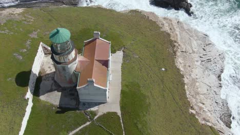 historic lighthouse on cliff side, drone descent