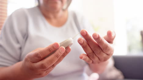 senior woman checking blood sugar level using glucometer at home