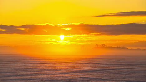 Mystische-Winterszene-Mit-Goldenem-Sonnenuntergang,-Der-Sich-An-Verschneiten-Wintertagen-Hinter-Waldbäumen-Versteckt---Schneebedecktes-Ackerland-Mit-Fliegenden-Wolken-über-Feldern-Und-Linsenfackeln-Von-Sonnenstrahlen-Im-Hintergrund---Zeitraffer