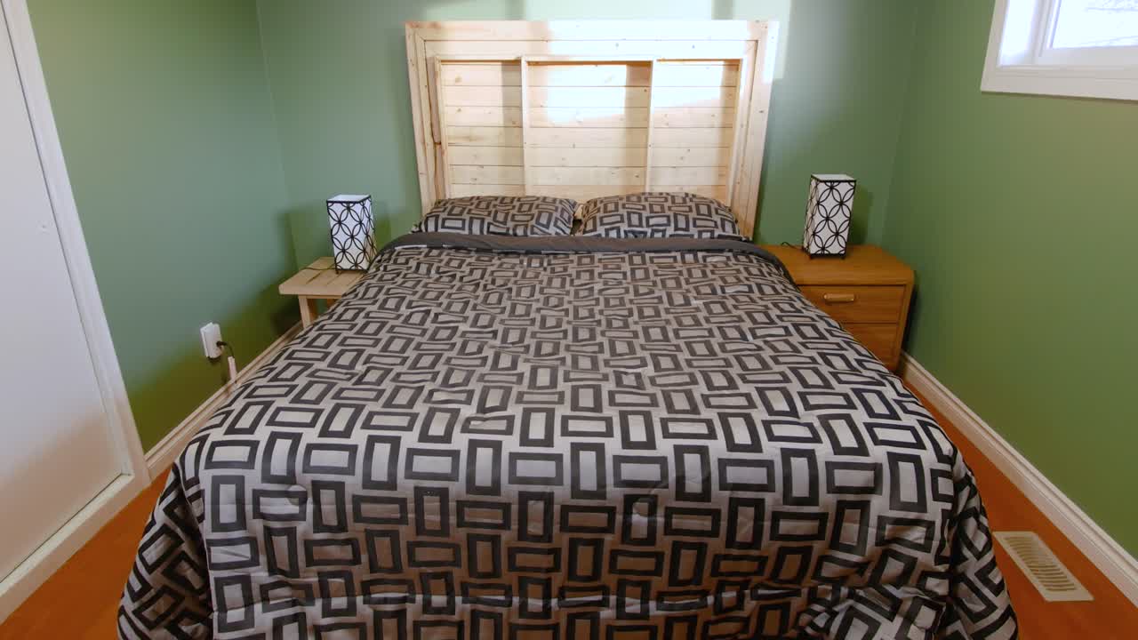 A slow tilt up showcasing a wooden accented green bedroom inside a family home