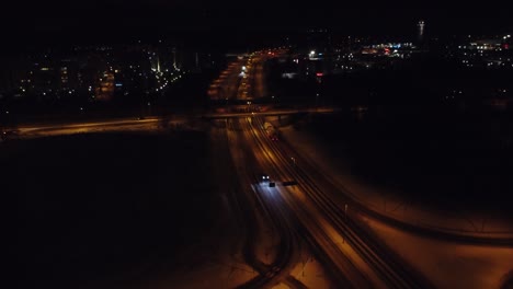 la antena nocturna en retirada se inclina hacia arriba para revelar el tráfico ligero de la ciudad en invierno