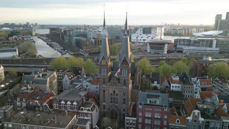 drone orbits above posthoornkerk church in downtown amsterdam at sunrise