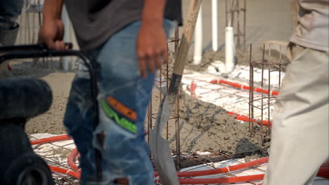 slow motion of fresh concrete mix being poured to make a bald at a construction site in mexico with various unrecognizable workers moving around