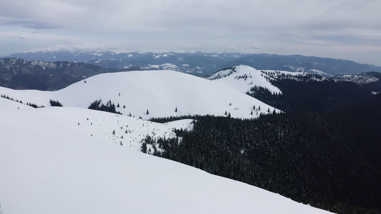 Vast snowy landscape of Iezer-Papusa Mountains, Romania, with forested valleys