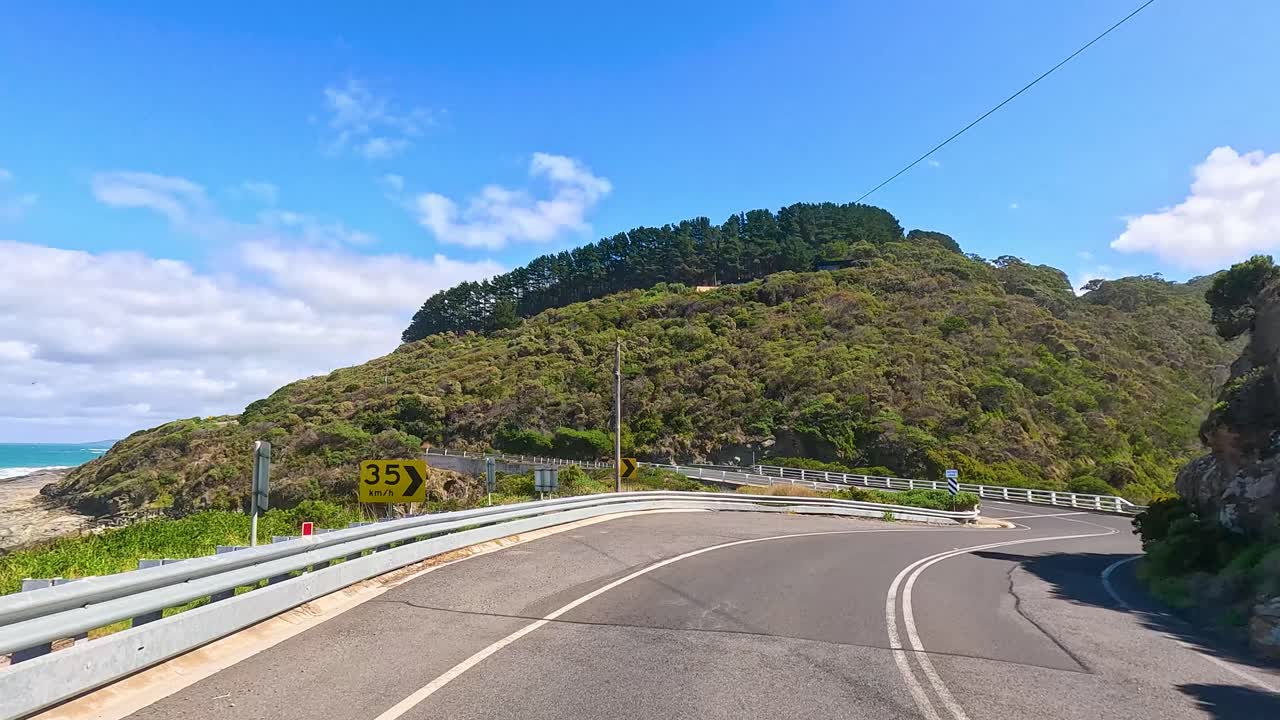 A 14-second video captures a scenic drive along the winding Great Ocean Road, showcasing lush greenery and ocean views under bright daylight