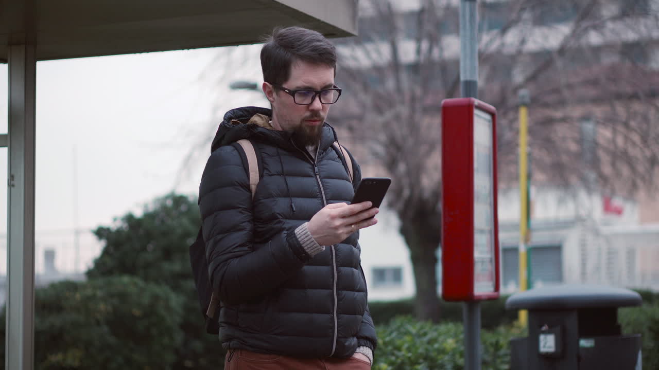 hombre usando un teléfono en una parada de autobús