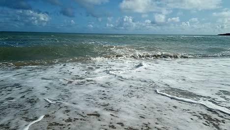 Olas-Del-Océano-En-Cámara-Lenta-Chapoteando-En-La-Pintoresca-Playa-De-La-Isla-De-Arena-Cielo-Azul-Relajante-Costa-Tranquila