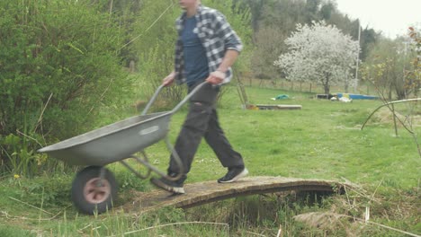 young man with wheelbarrow crossing bridge