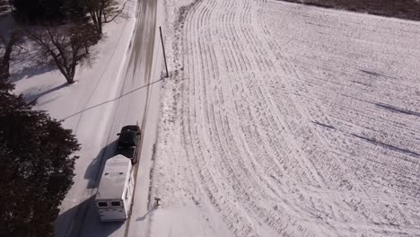 vehicle tow horse trailer on icy rural road, aerial drone shot