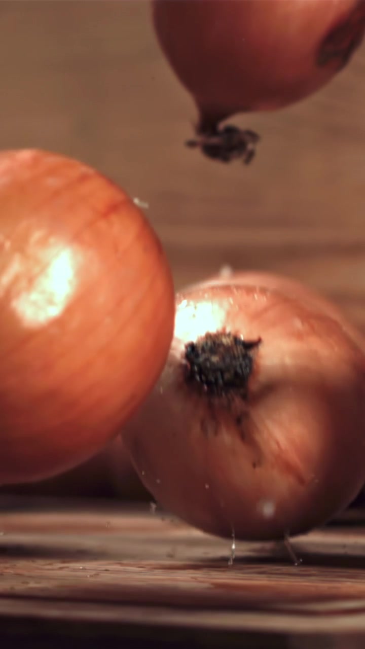 Cebollas frescas cayendo sobre una mesa de madera rústica en cámara lenta