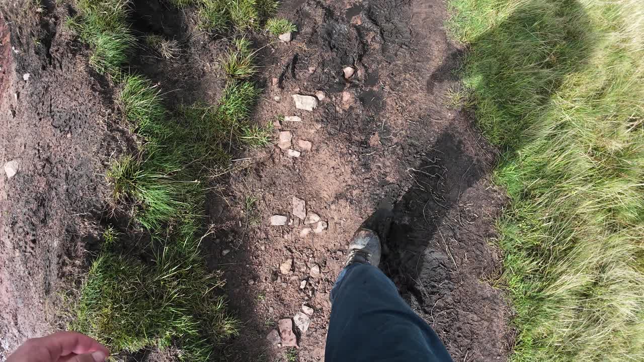 POV walking along the rocky trail of Pen y Fan in the Brecon Beacons, Wales. The hiker’s boots step on rugged stones, capturing the essence of adventure, hiking, and outdoor exploration