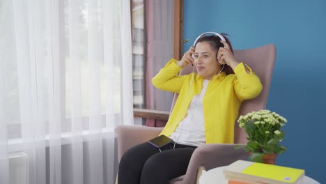 Woman-looking-out-the-window-and-listening-to-music-with-headphones.