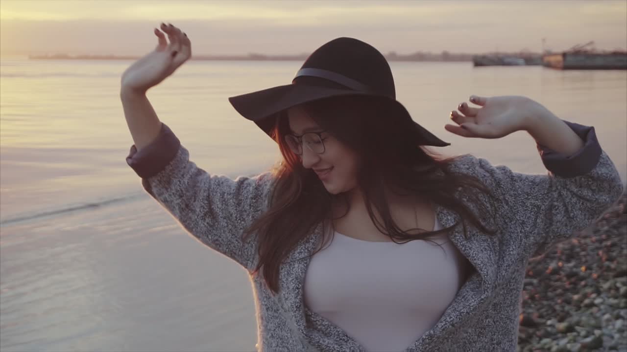 женщина наслаждается закатом на берегу воды