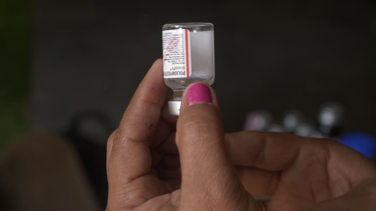 A woman healthcare professional drawing Poliomyelitis poliovirus vaccine into syringe from a vial, National Polio Immunization Drive by Ministry of Women and Family Welfare, Bihar