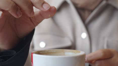 woman adding sugar to her coffee