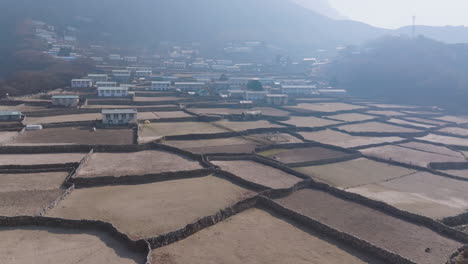 drone shot of phortse village at sunrise with dry farming lands, morning dew, smoke haze, diverse architecture buildings, and religious setting in himalayas peace and calm nature