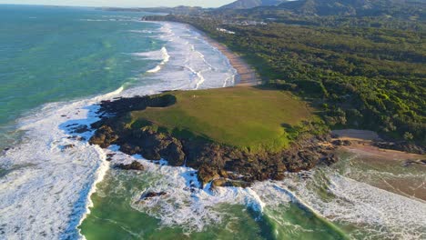 aerial view of green bluff headland and sapphire beach - ocean waves at moonee beach in sydney, nsw, australia