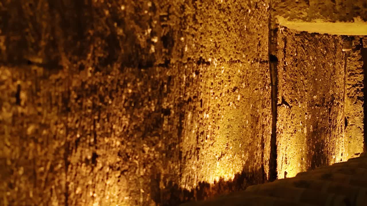 A warmly lit stone corridor with textured walls and ambient shadows, creating a mysterious and inviting atmosphere.