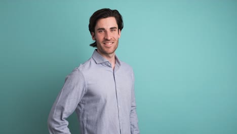 handsome man smiling at camera in blue studio