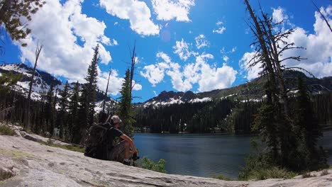 a time lapse of a man in his 30's sitting by a mountain lake