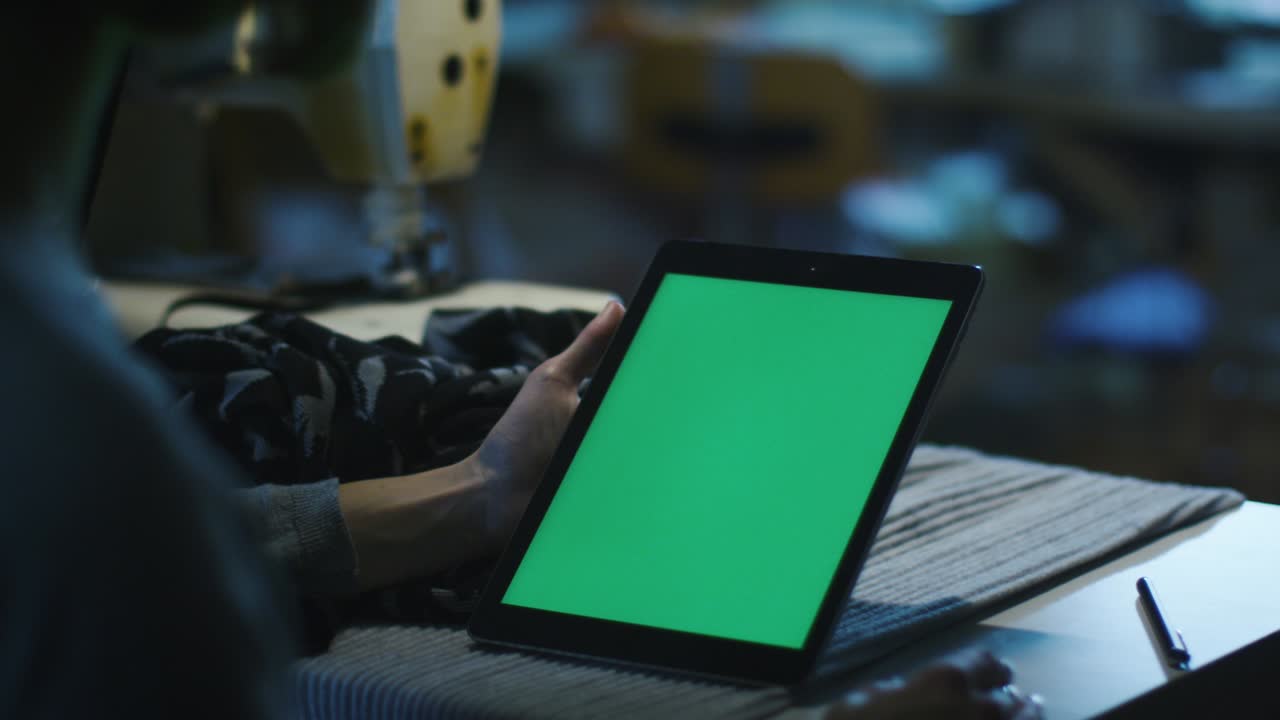 바느질사는 포트레이트 모드에서 모의 화면을 가진 태블릿을 들고 있습니다.