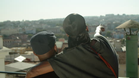 back view of gays hugging and admiring cityscape from rooftop