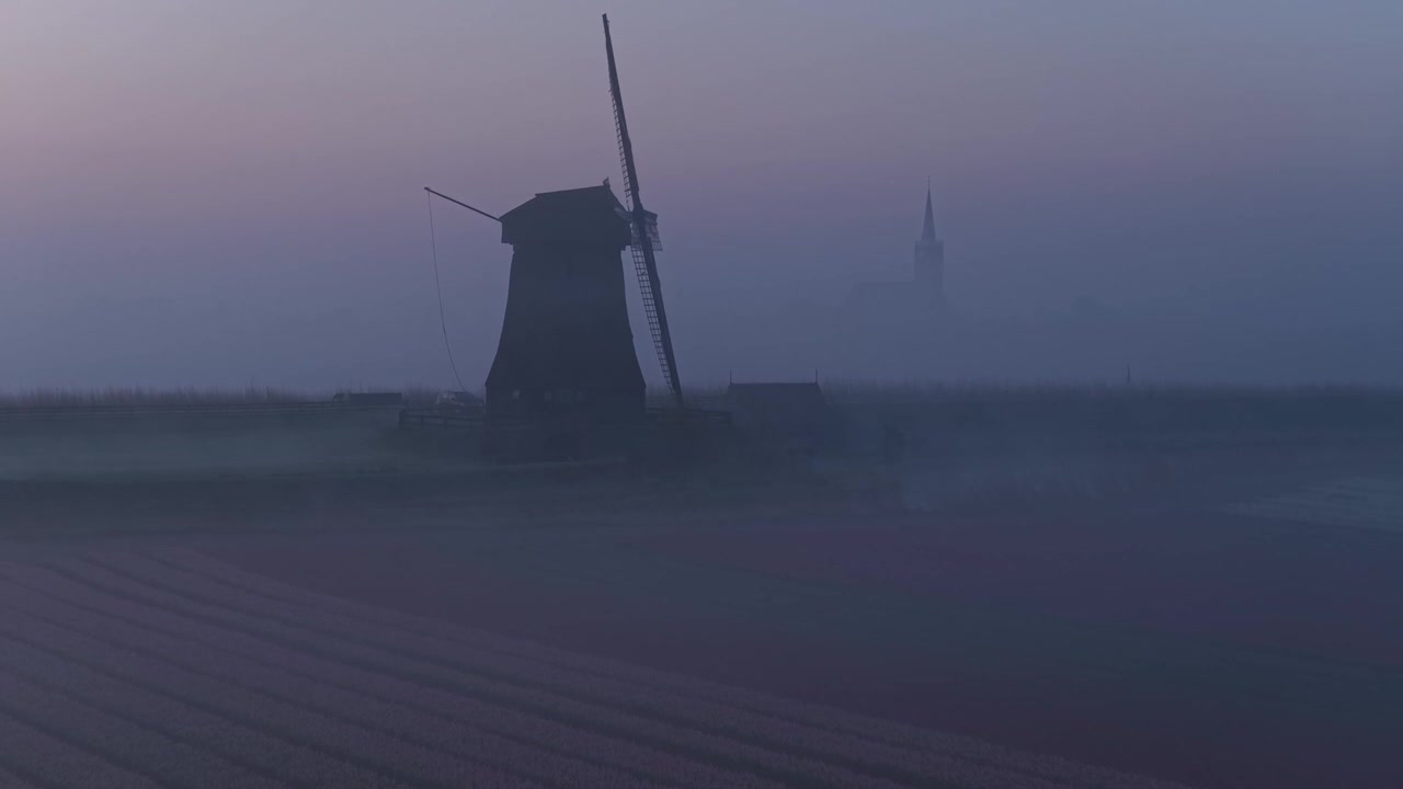 Nederlandsk vindmølle dukker opp fra morgentåke ved soloppgang