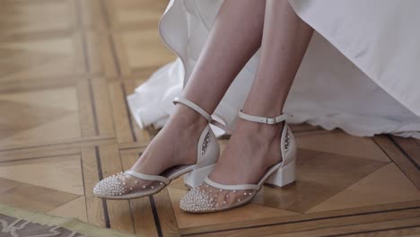 bride getting ready and putting on her beautiful white shoes