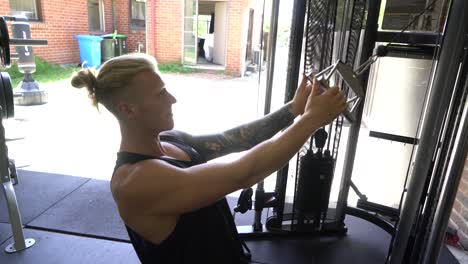 Tattoo man muscles in home gym doing incline cable lat row