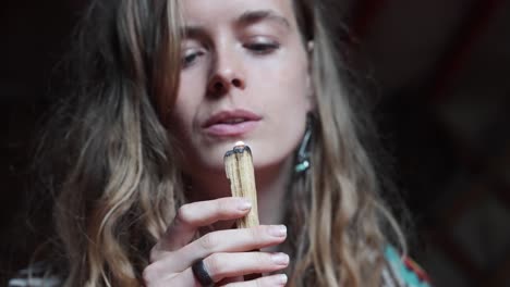 slow motion static close-up of a young hippie woman burning a sacred wood incense in slow motion