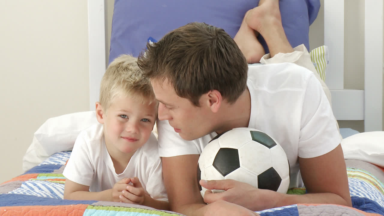 padre e hijo jugando con una pelota en el dormitorio