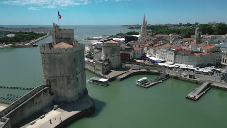 ferry boat entering in old port of la rochelle with chain and saint nicolas towers, france