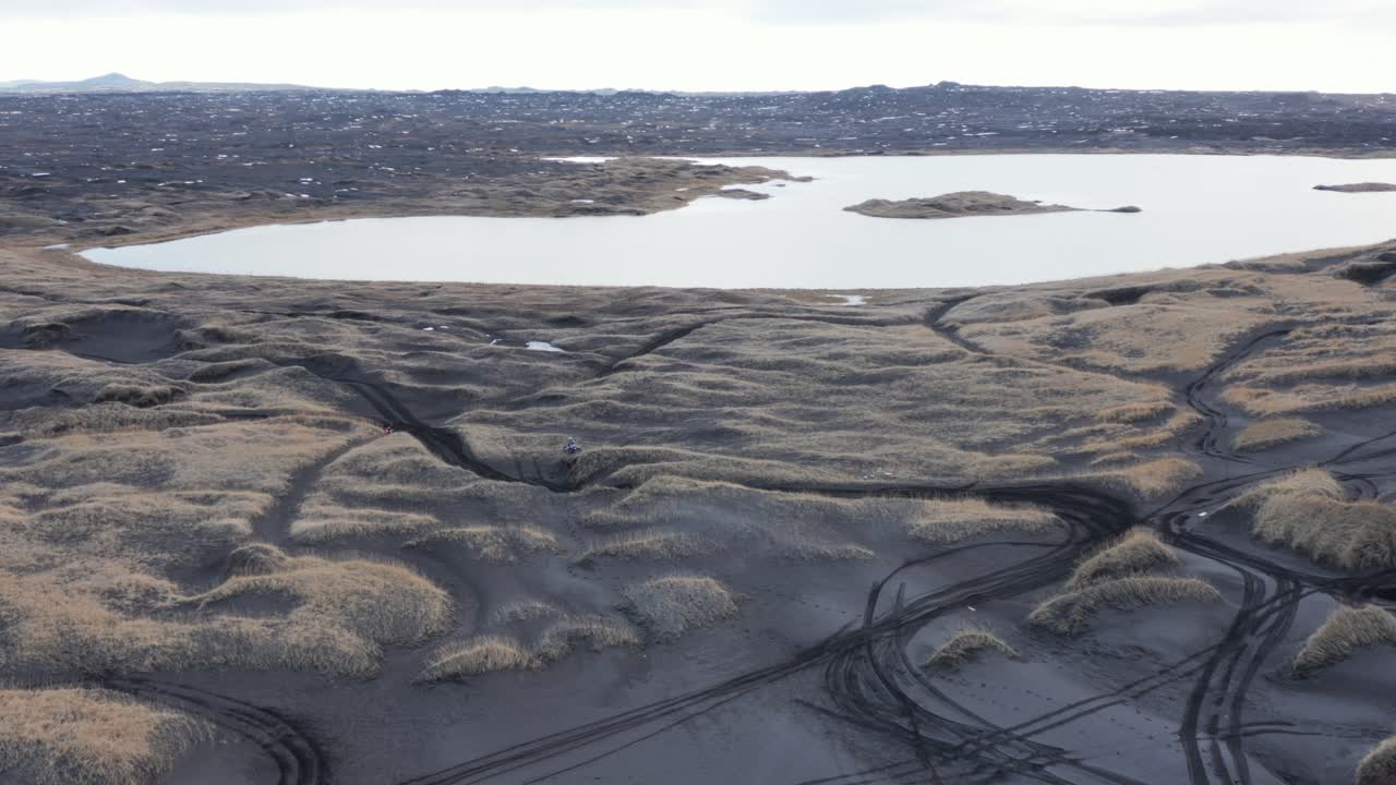 piloto de motocross en bicicleta a través de dunas de hierba en islandia, antena