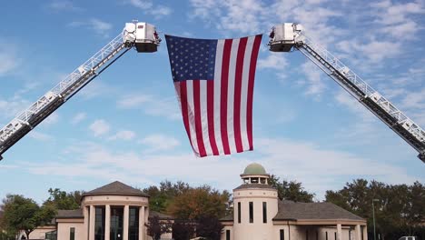 A-large-American-Flag-is-suspended-between-two-ladders-waves-over-several-mortuary-buildings