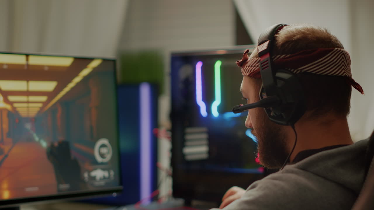 Focused man gamer putting headset playing shooter online video game