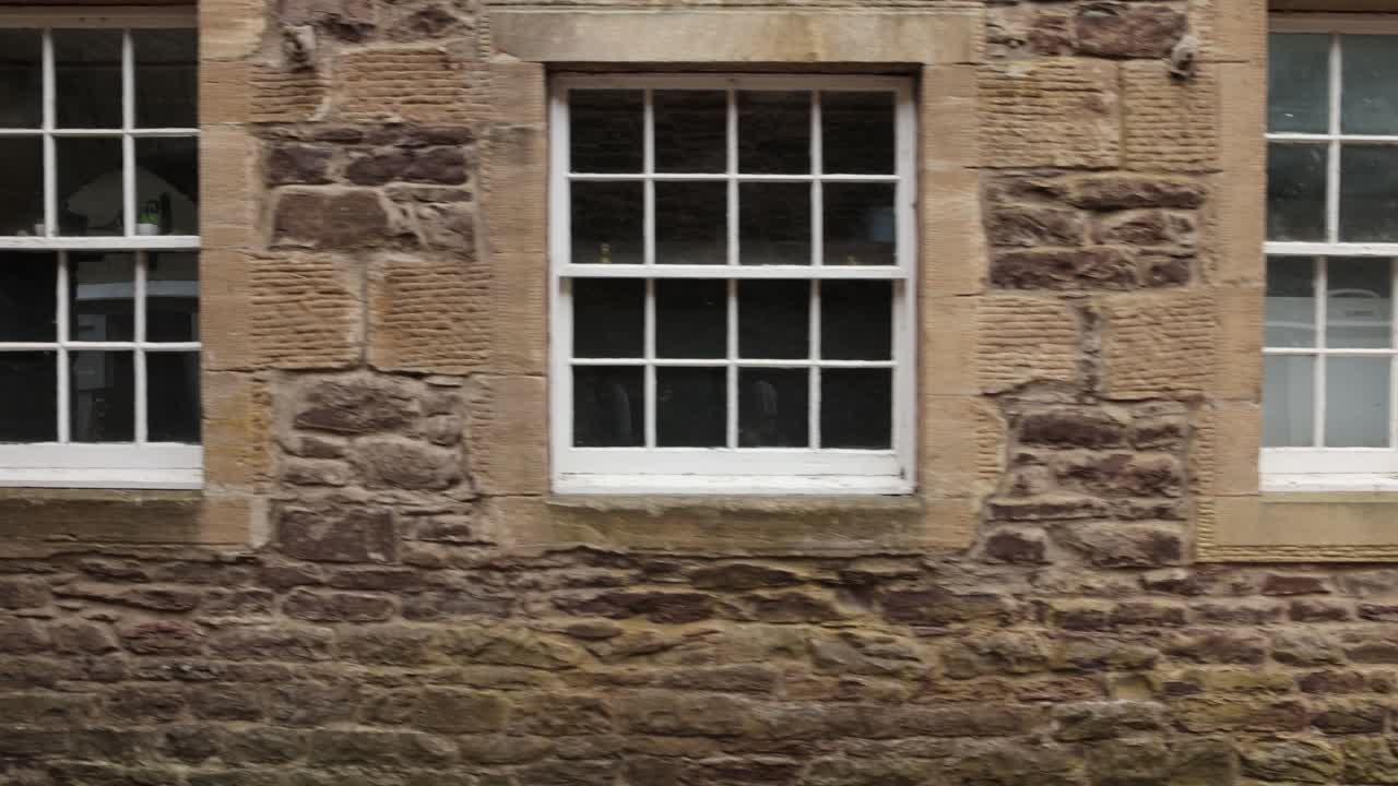 Slow establishing shot of antique building windows at New Lanark