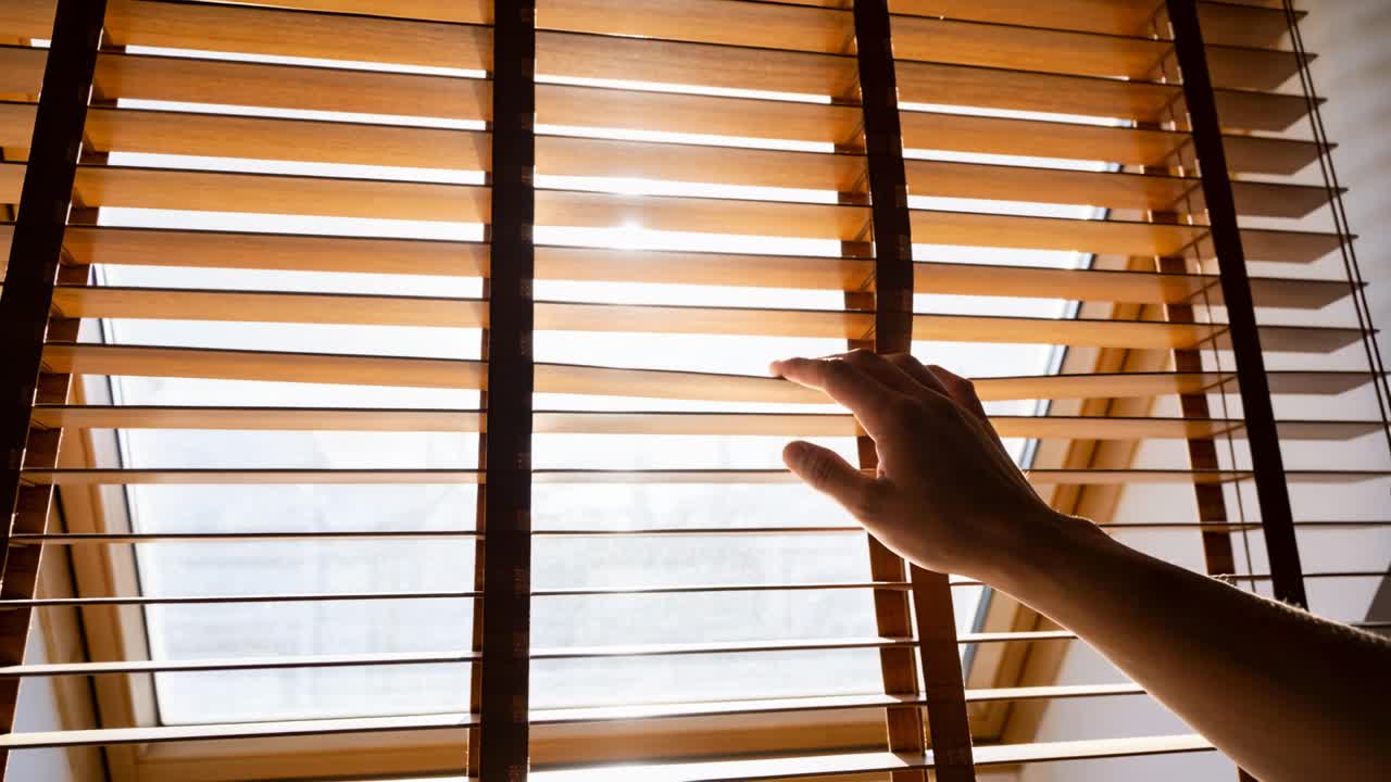 Reaching right hand responding to sun, adjusting wooden slats on skylight along cords, copy space