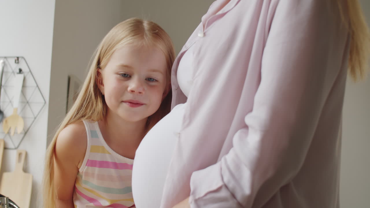 어린 소녀 가 임신 한 어머니 의 배 를 만지고 있다
