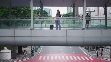 woman on a pedestrian bridge in a city