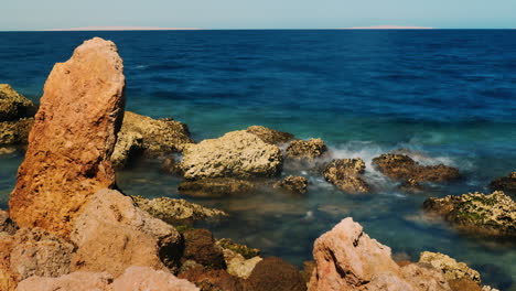 Surf-At-The-Rocks---Red-Stone-On-A-Background-Of-Blue-Sea-4k-Timelapse-Video