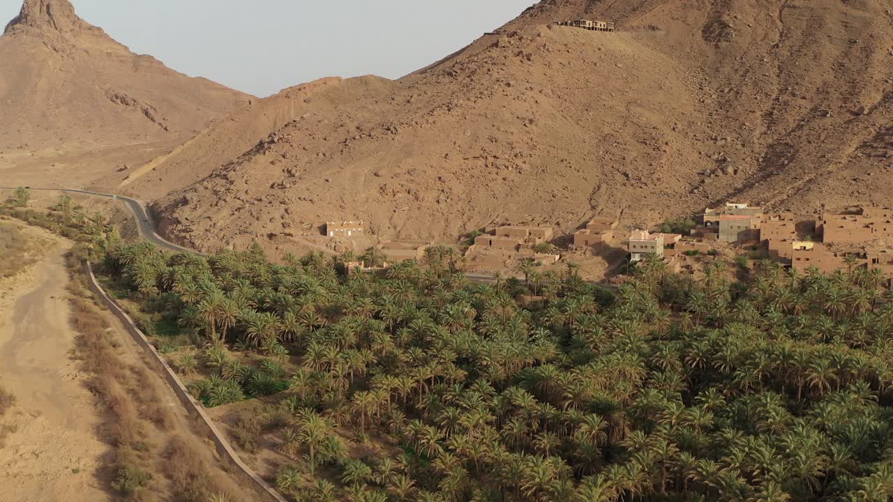 Villaggio marocchino circondato da palme e montagne rocciose, valle del Draa