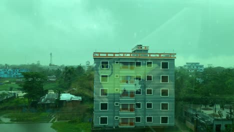 Smartphone-films-raindrops-on-window-during-monsoon,-capturing-reflections-inside-apartment