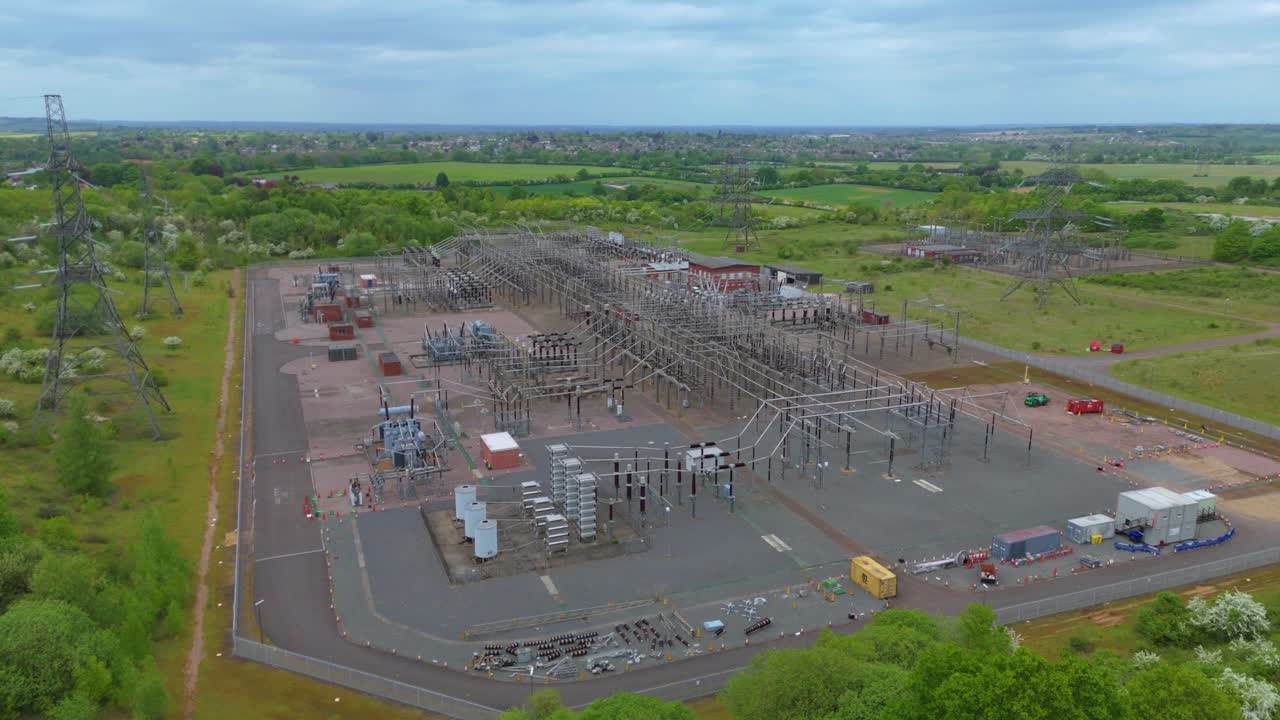 Aerial drone view of an electric power substation near Stevenage, England. Showing energy infrastructure with pylons, cables, and connections to renewables and fossil fuels.