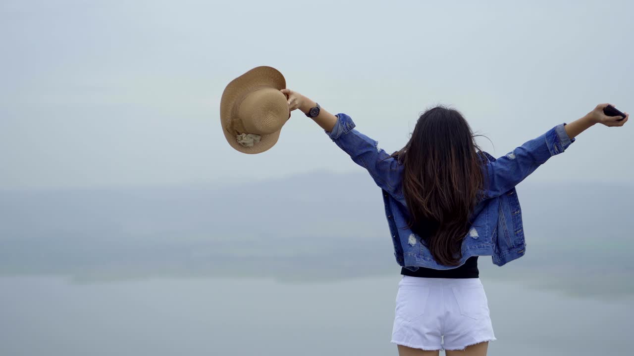아시아 여성들은 행복하고 무관심한 여름, 팔을 들어 올려 웃고 있습니다.