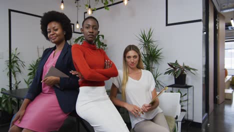 portrait of three diverse female office colleagues smiling at office