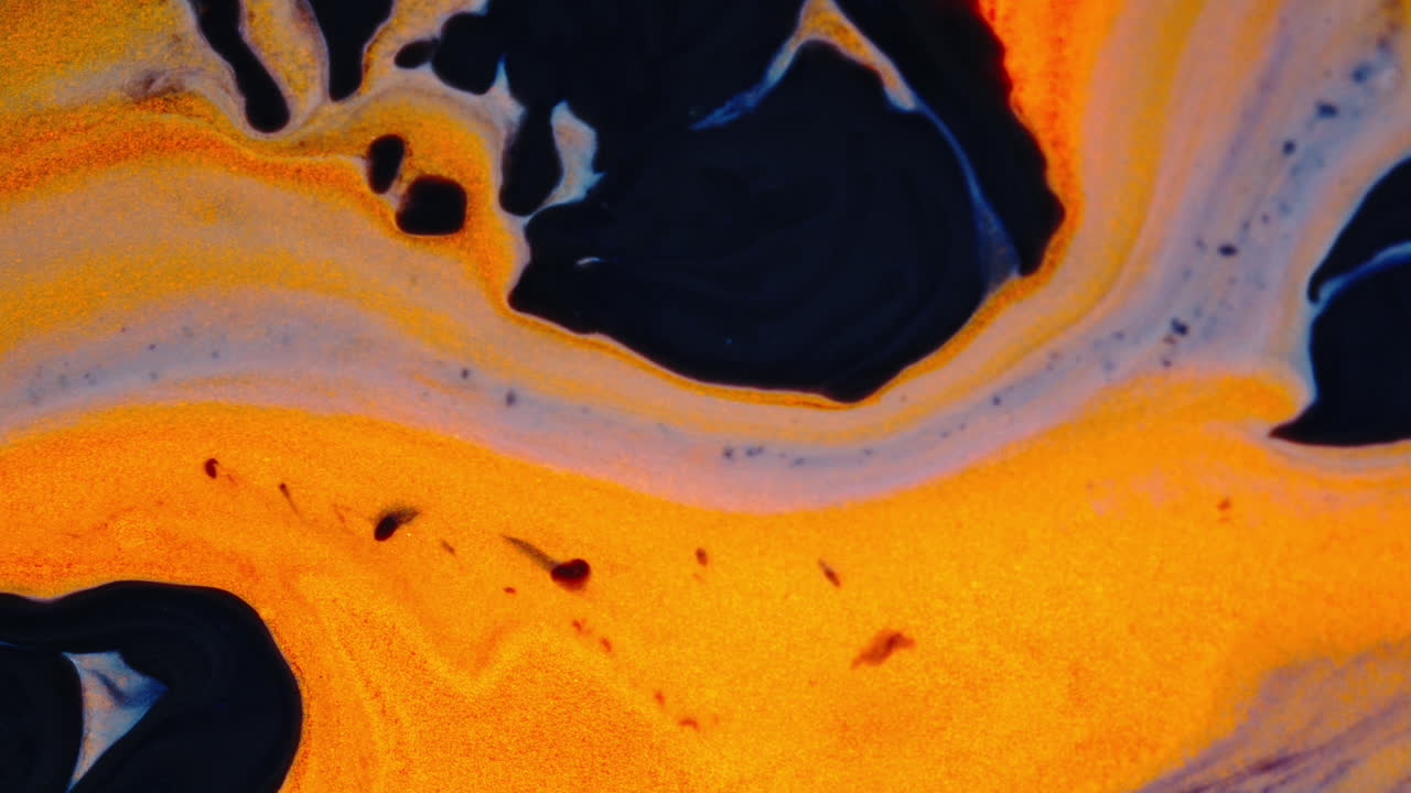 Flowing ink and vibrant colors blend together in a macro shot, showcasing smooth, artistic patterns
