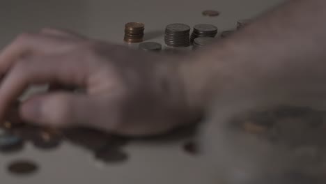 cleaning up a pile of various coins stacked and laying on a table