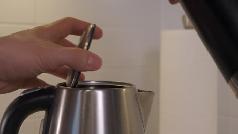 Water-being-poured-from-a-black-water-bottle-into-kettle-to-be-boiled-in-slow-motion