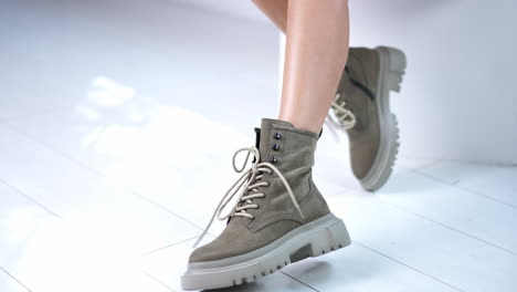 demonstrating grey stylish modern boots with laces. fashionable winter footwear with tractor soles on female hands. close up. white backdrop.