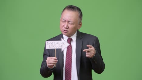 성숙 한 일본인 사업가 가 종이 표지판 을 들고 있다